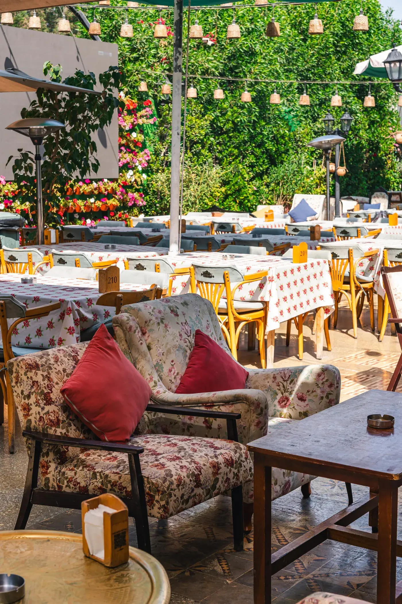 The garden terrace at Al Falamanki: a floral armchair under a pergola hung with lanterns