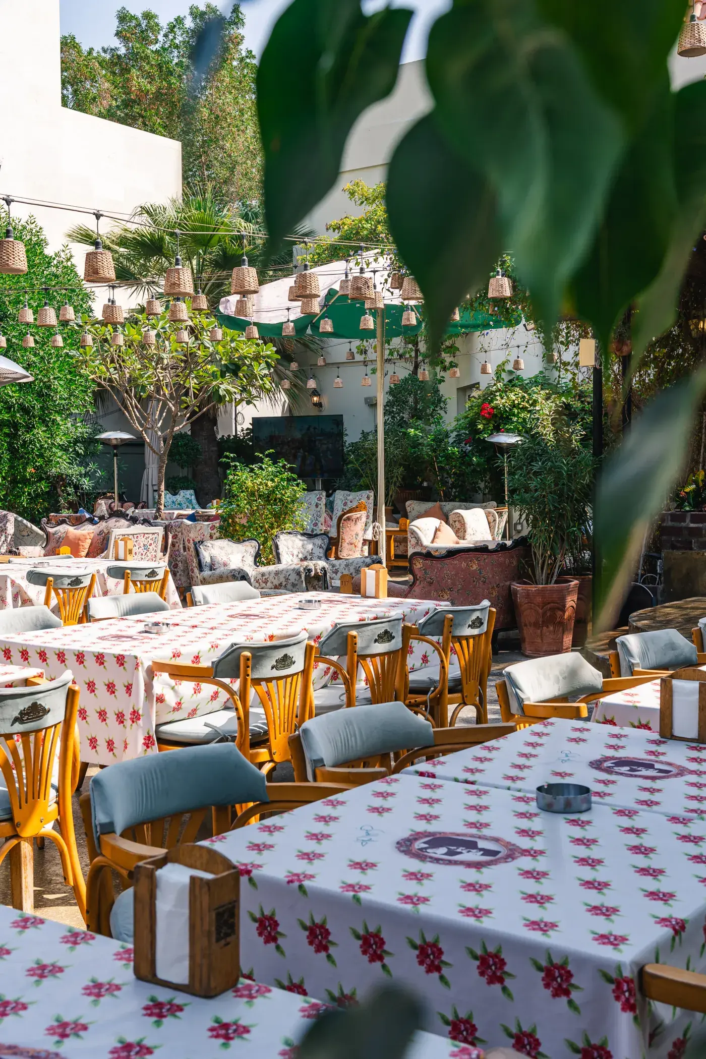 Tables laid with floral cloths under the trees, Al Falamanki Dubai