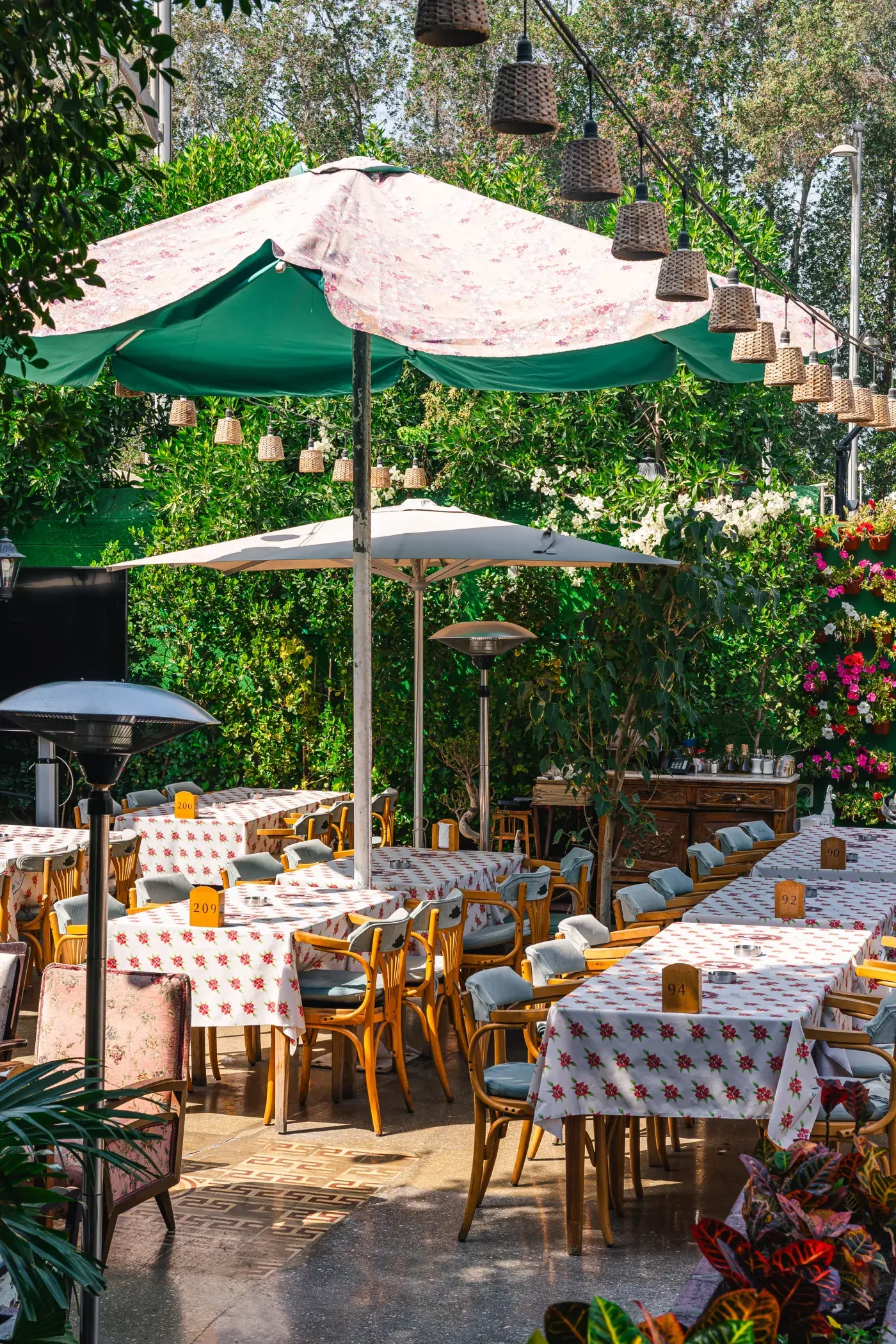 Green parasols over floral-cloth tables on the garden terrace, Al Falamanki Dubai