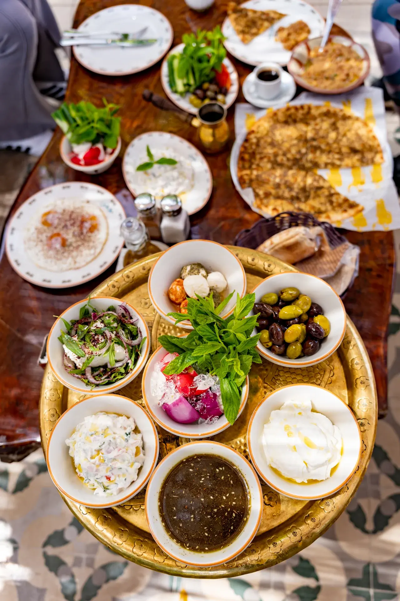 A brass tray of mezze: labneh, olives, tabbouleh and hot bread, from above, Al Falamanki Antelias