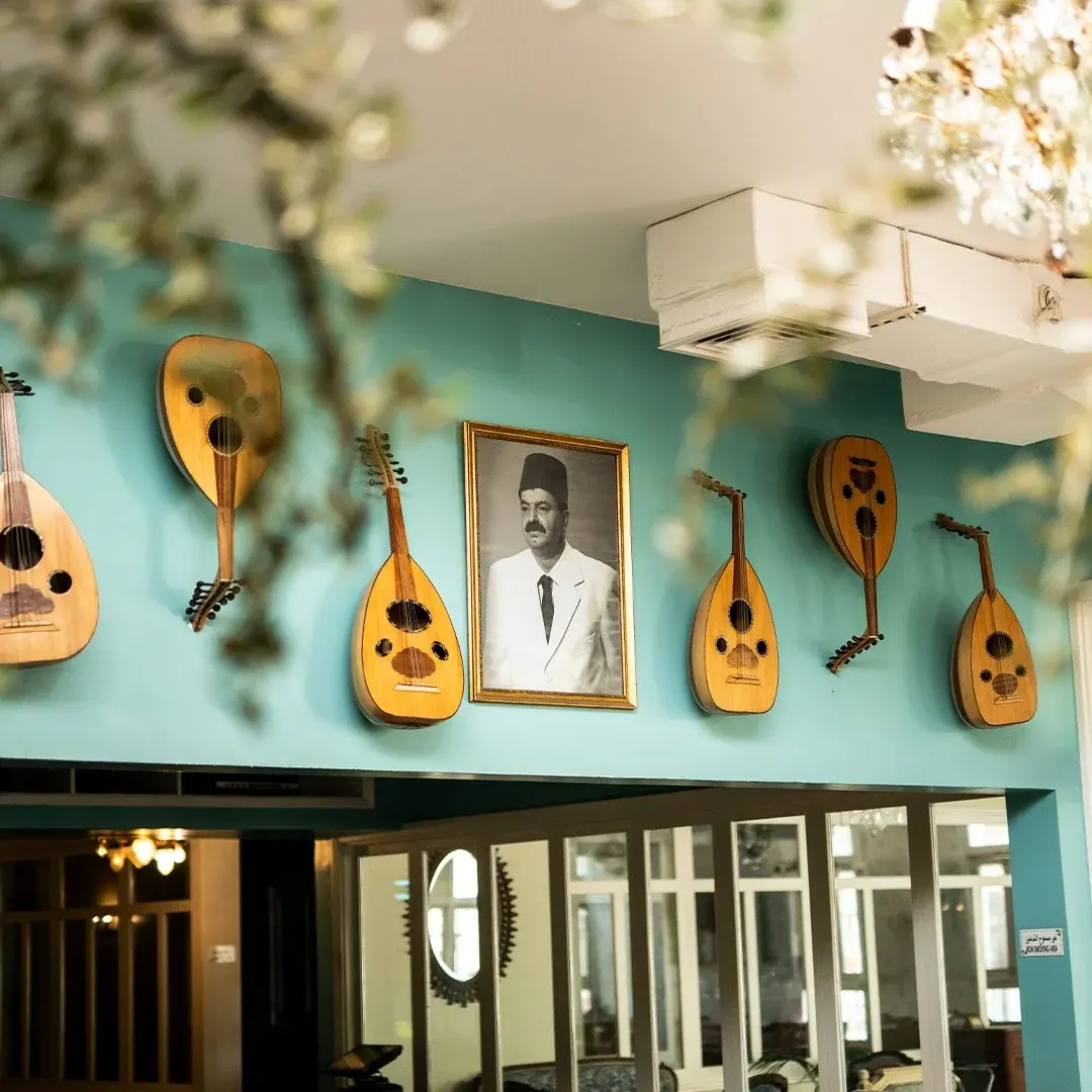 Ouds hanging on the teal wall around a framed portrait, Al Falamanki Doha