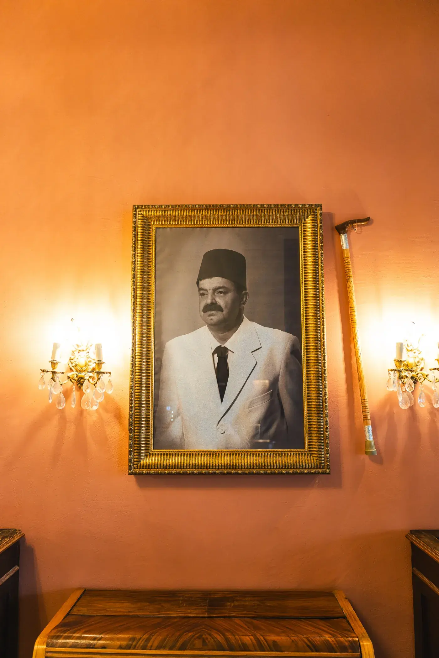 A framed portrait lit by wall lamps on the ochre wall, Al Falamanki Riyadh